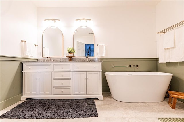 full bathroom with a sink, double vanity, and a freestanding tub