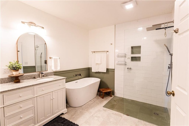 bathroom with a freestanding tub, wainscoting, a tile shower, and vanity