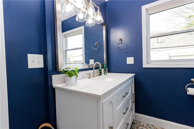 bathroom featuring a notable chandelier, vanity, and baseboards