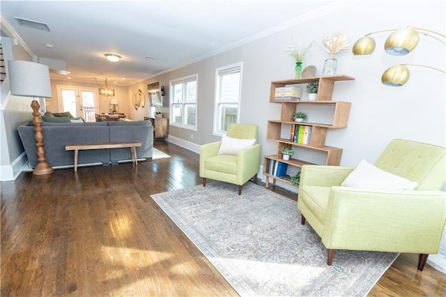 living area with baseboards, visible vents, wood finished floors, and ornamental molding