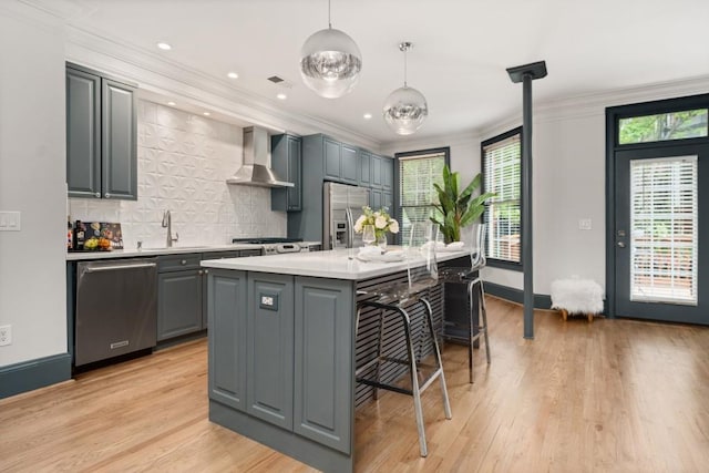 kitchen featuring wall chimney range hood, decorative backsplash, visible vents, light wood-type flooring, and stainless steel appliances