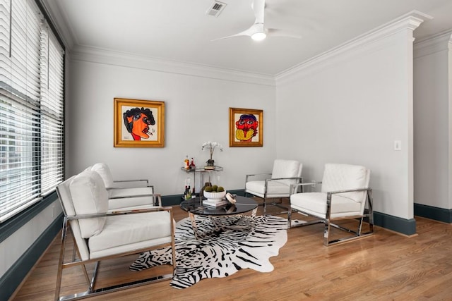 living area with a ceiling fan, baseboards, ornamental molding, and wood finished floors