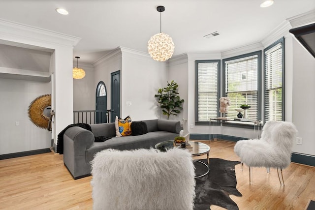 living area with crown molding, wood finished floors, a healthy amount of sunlight, and a premium fireplace