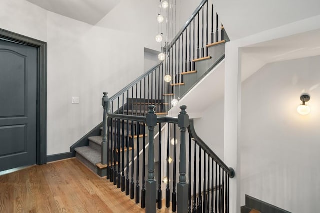 stairway featuring a towering ceiling and wood finished floors