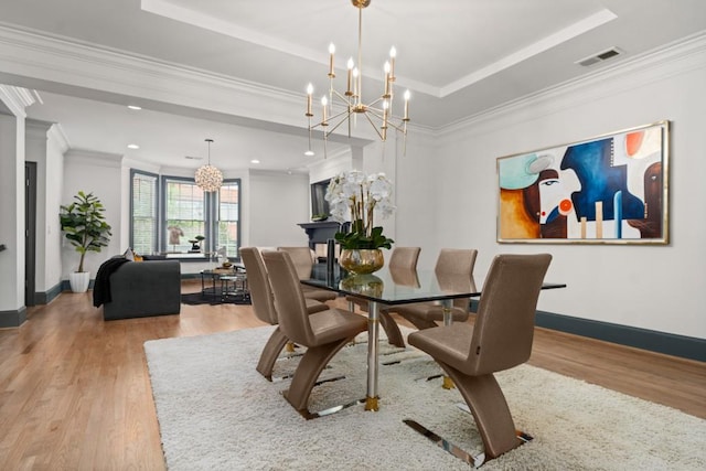 dining area featuring crown molding, a chandelier, baseboards, wood finished floors, and a tray ceiling