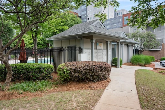 exterior space featuring stucco siding, fence, a shingled roof, and mail area