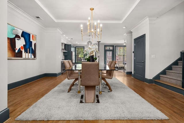 dining area featuring an inviting chandelier, ornamental molding, wood finished floors, and visible vents