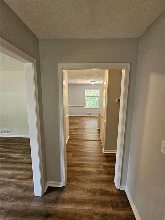 hallway featuring a textured ceiling and dark hardwood / wood-style flooring