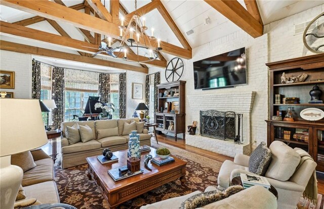 living room featuring an inviting chandelier, a brick fireplace, beam ceiling, and wood-type flooring