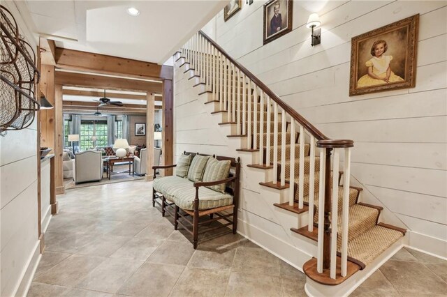 stairway featuring wooden walls and ceiling fan