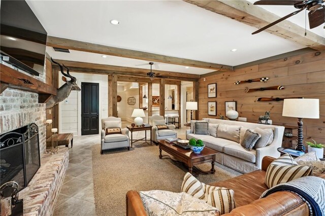 tiled living room featuring beam ceiling, ceiling fan, and a brick fireplace