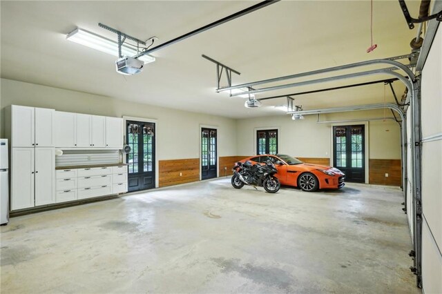 garage with french doors, a garage door opener, and white fridge