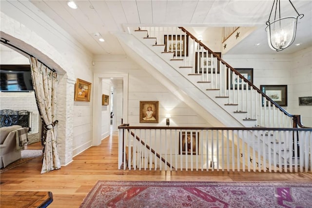 stairs featuring wood-type flooring, wood walls, and a chandelier