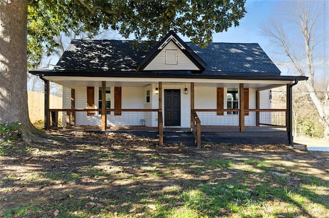 farmhouse-style home with a porch and roof with shingles