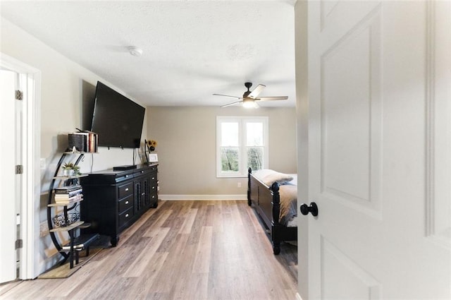 bedroom with light wood-type flooring, baseboards, and a ceiling fan