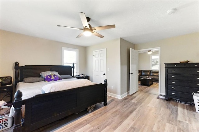 bedroom with a ceiling fan, light wood-type flooring, multiple windows, and baseboards