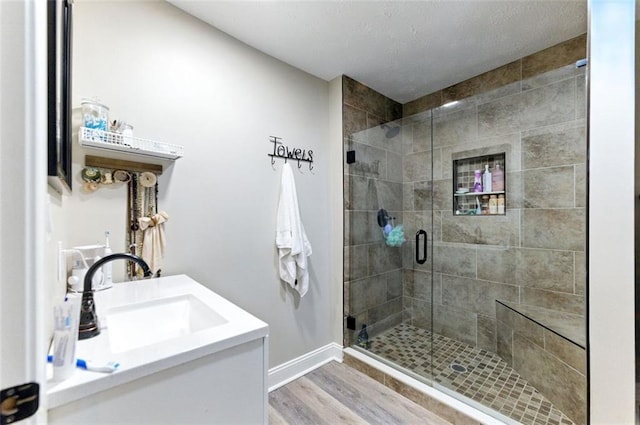 full bathroom with baseboards, a shower stall, vanity, and wood finished floors