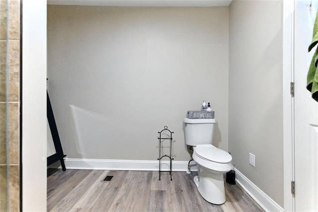 bathroom with baseboards, toilet, and wood finished floors