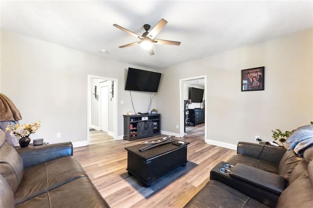 living room with a ceiling fan, baseboards, and wood finished floors