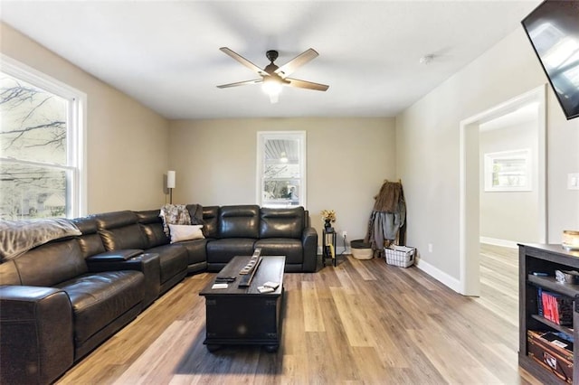 living area with a ceiling fan, light wood-style flooring, and baseboards