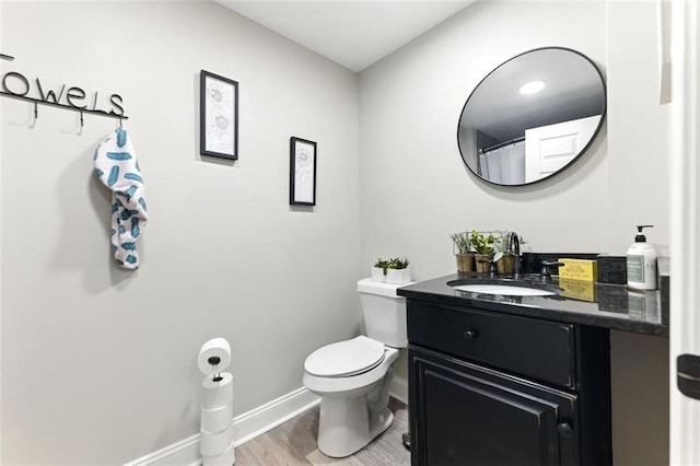 bathroom with vanity, wood finished floors, toilet, and baseboards