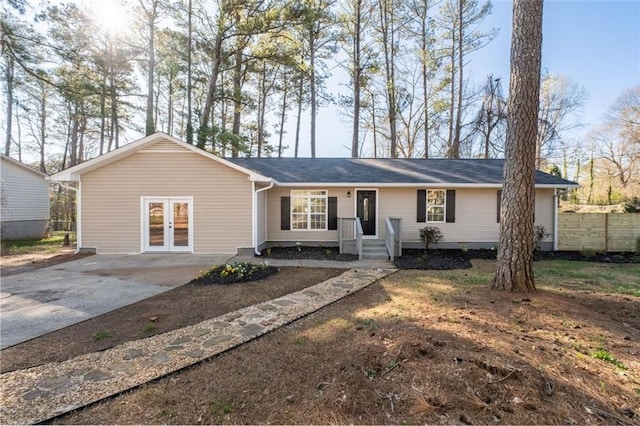 ranch-style home featuring concrete driveway, french doors, and fence