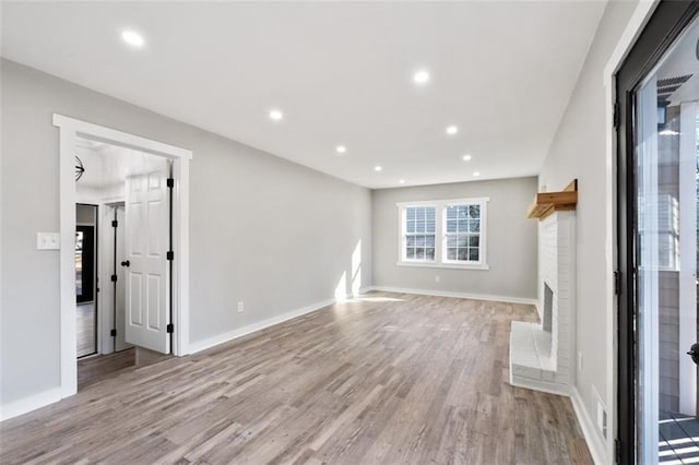 unfurnished living room with a fireplace, recessed lighting, light wood-style flooring, and baseboards