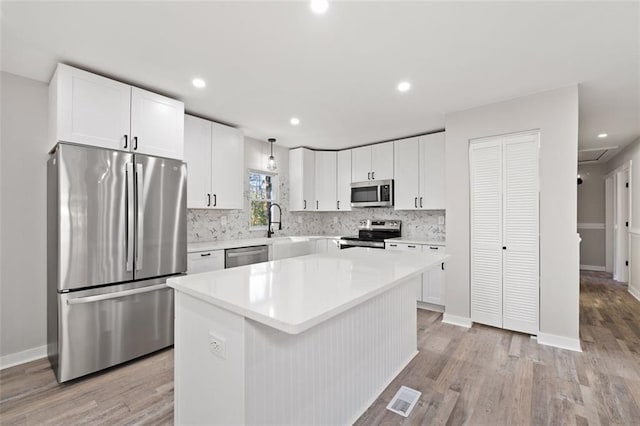 kitchen featuring white cabinets, light wood-style floors, backsplash, and appliances with stainless steel finishes
