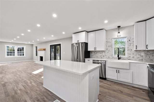 kitchen featuring a sink, backsplash, wood finished floors, and stainless steel appliances