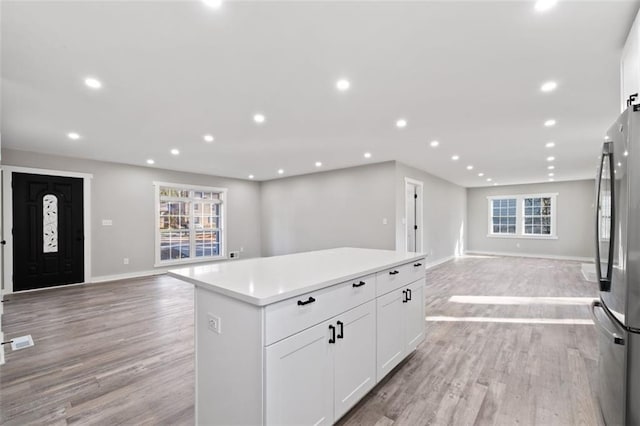 kitchen featuring recessed lighting, open floor plan, a center island, and freestanding refrigerator