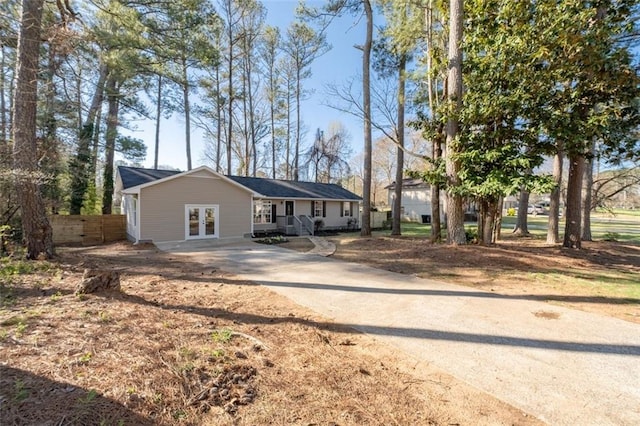 single story home with french doors, driveway, and fence