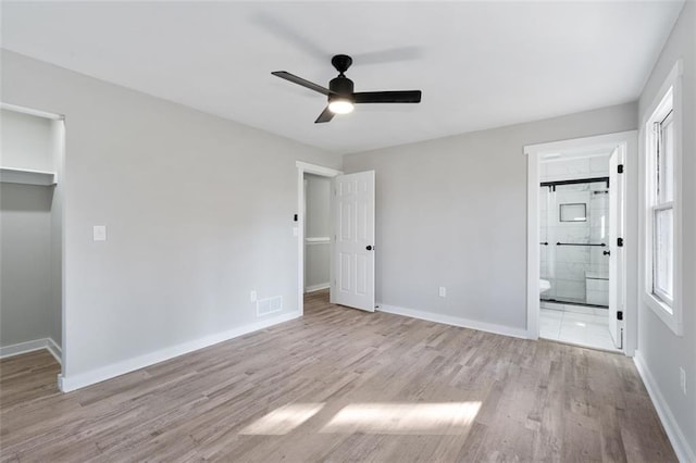 unfurnished bedroom featuring a closet, ensuite bath, visible vents, wood finished floors, and baseboards