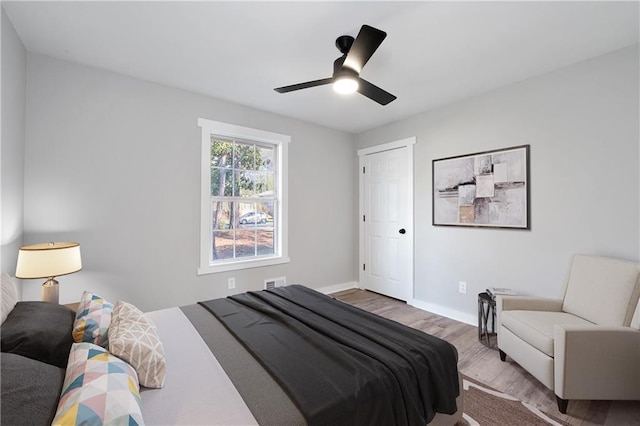 bedroom featuring wood finished floors, ceiling fan, baseboards, and visible vents