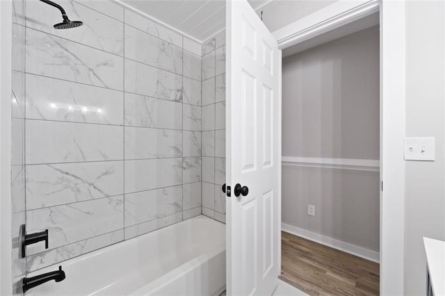 full bathroom with wood finished floors, baseboards, and washtub / shower combination