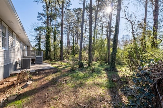 view of yard featuring central air condition unit, a wooden deck, and stairs