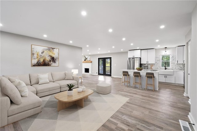 living area with recessed lighting, light wood-style floors, baseboards, and visible vents