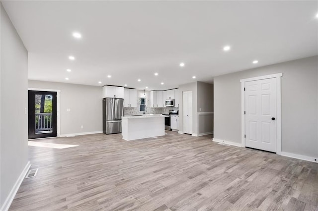 unfurnished living room featuring light wood finished floors, baseboards, visible vents, and recessed lighting