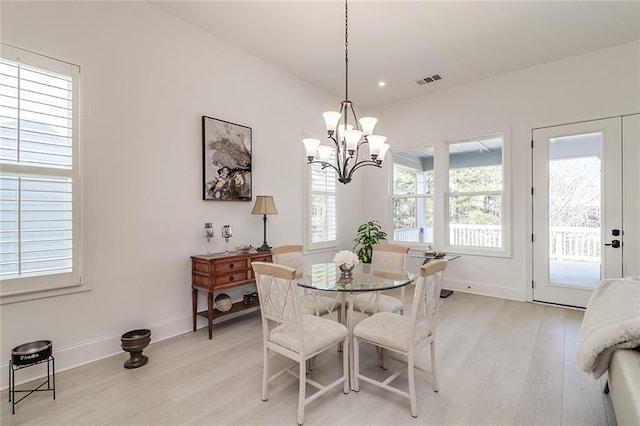 dining space featuring a wealth of natural light, a notable chandelier, and light wood-type flooring