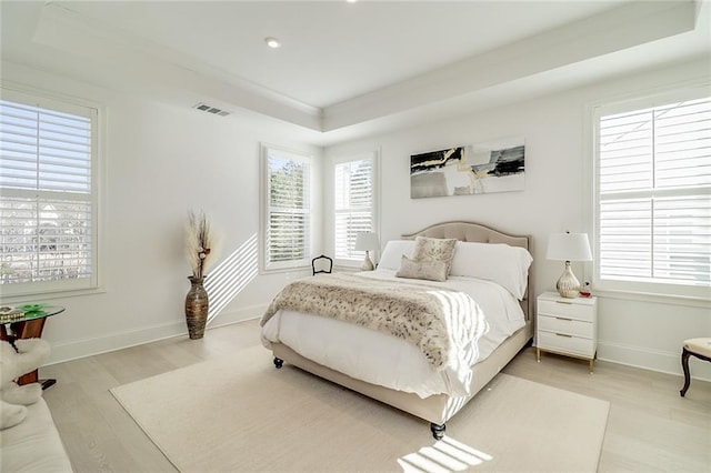 bedroom featuring a tray ceiling and light wood-type flooring