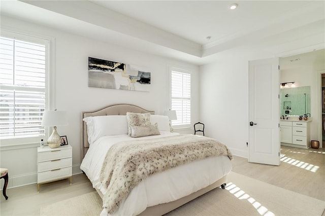 bedroom featuring multiple windows, ensuite bath, and light hardwood / wood-style floors