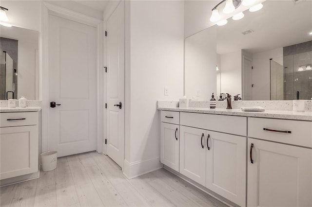 bathroom featuring walk in shower, vanity, and hardwood / wood-style floors