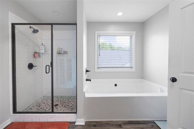 1016 Buckeye Ln, Villa Rica, GA 30180 - bathroom featuring a bath, wood finished floors, a stall shower, and recessed lighting