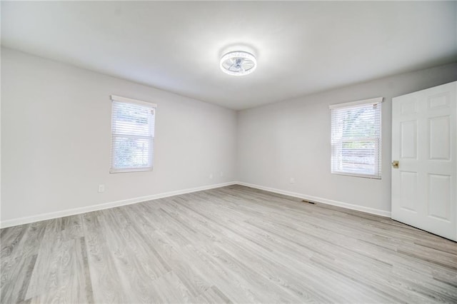 spare room with light wood-type flooring and a wealth of natural light