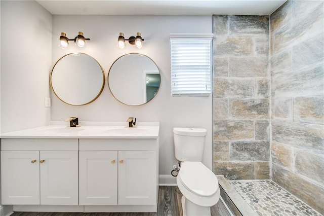 bathroom with vanity, tiled shower, and toilet