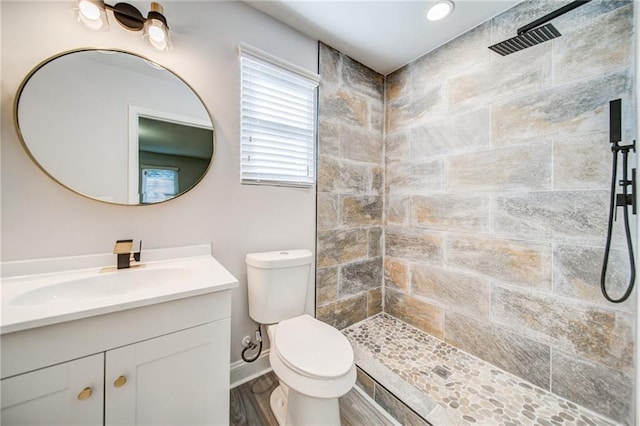 bathroom with vanity, toilet, and a tile shower