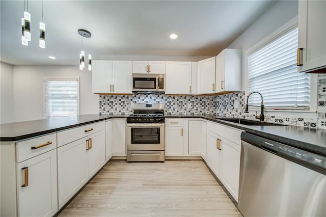 kitchen with stainless steel appliances, decorative light fixtures, sink, and white cabinets