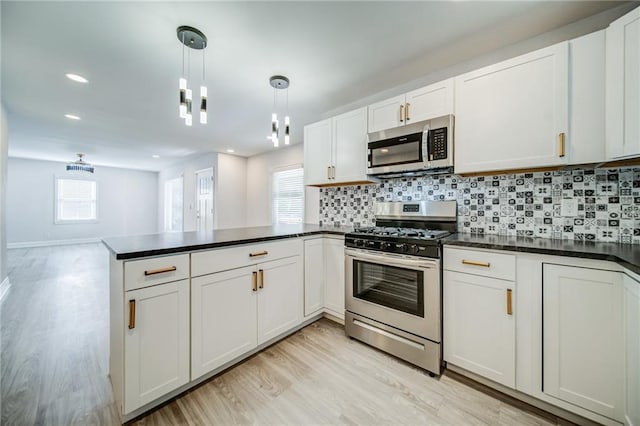 kitchen featuring pendant lighting, appliances with stainless steel finishes, white cabinetry, decorative backsplash, and kitchen peninsula