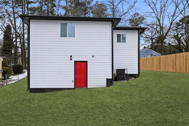 rear view of house featuring central AC unit and a yard