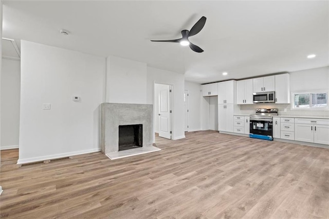 unfurnished living room with ceiling fan, a fireplace, and light hardwood / wood-style floors