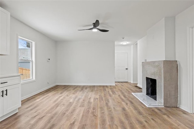 unfurnished living room with ceiling fan, a fireplace, and light hardwood / wood-style floors